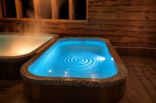Illuminated rectangular spa pool with rippling water at night