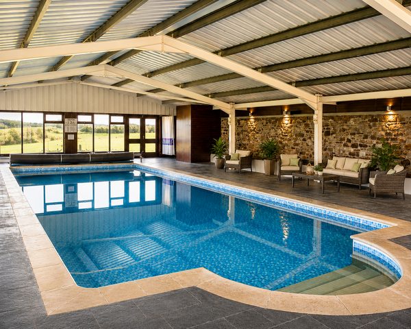Indoor pool with garden views and lounge seating