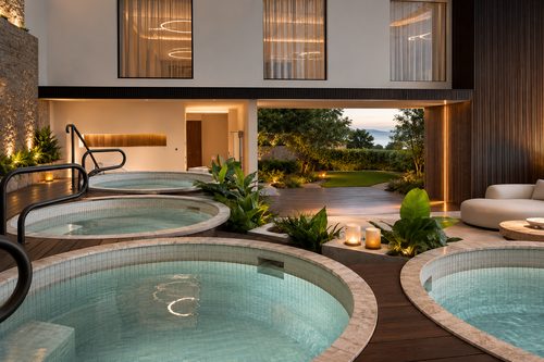 Multiple circular hot tubs on a terrace at dusk